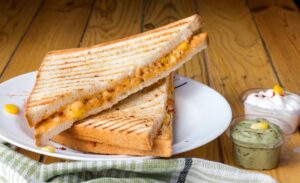 Close-up of a person grilling sandwiches in a skillet, with melted cheese and golden bread visible.