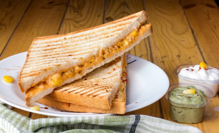 Close-up of a person grilling sandwiches in a skillet, with melted cheese and golden bread visible.